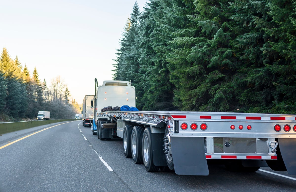 Semi truck with empty flatbed trailer on a winter highway